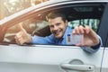 Young smiling man sitting in the car and showing his new driver license with thumb up sign Royalty Free Stock Photo