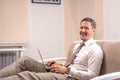 A young  smiling man sitting on sofa and working on his laptop Royalty Free Stock Photo