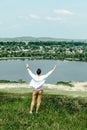 young smiling man standing on cliff catching wind