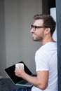 Young smiling man in t-shirt and glasses, holding a cup of coffee Royalty Free Stock Photo