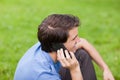 Young smiling man talking on the phone while sitting in a park Royalty Free Stock Photo