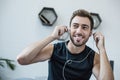 Young smiling man in tanktop putting on earbuds