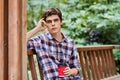 Man in the forest in wooden summerhouse with red paper cup Royalty Free Stock Photo