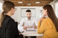 Young smiling man in white shirt holding pencil in hands while waiting results of job interview