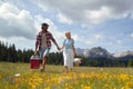 Young smiling man and woman in love holding hands and walking in nature on a beautiful day. Couple is holding picnic equipment Royalty Free Stock Photo