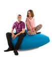 Young smiling man and woman sitting on blue beanbag sofa isolate Royalty Free Stock Photo