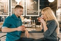 Young smiling man and woman together talking in coffee shop sitting near bar counter, couple of friends drinking tea, coffee Royalty Free Stock Photo