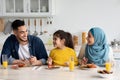 Young Smiling Middle Eastern Parents And Little Daughter Having Breakfast In Kitchen Royalty Free Stock Photo