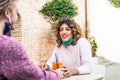 Young smiling millenial friends holding hands in a cocktail bar restaurant outdoor wearing protective face mask during happy hour Royalty Free Stock Photo