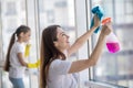 Young smiling mom and daughter washing a window.