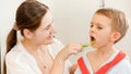 Young smiling mother brushing and cleaning teeth of her little son with tothbrush. Concept of child dental hygiene and Royalty Free Stock Photo