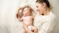 Young smiling mother lying on bed and hugging her little baby son Royalty Free Stock Photo