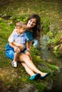 Young smiling mother sit on grass with her little son Royalty Free Stock Photo