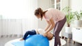 Young smiling mother stretching and doing exercises with her little baby son on fitball at home. Concept of child healthcare, kids Royalty Free Stock Photo