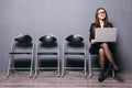 Young smiling office worker woman sitting on wood floor chair using mobile laptop computer prepare interview meeting file in gray Royalty Free Stock Photo