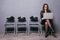 Young smiling office worker woman sitting on wood floor chair using mobile laptop computer prepare interview meeting file in gray Royalty Free Stock Photo