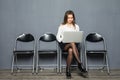 Young smiling office worker woman sitting on wood floor chair using mobile laptop computer prepare interview meeting file in gray Royalty Free Stock Photo