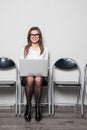 Young smiling office worker woman sitting on wood floor chair using mobile laptop computer prepare interview meeting file in offic Royalty Free Stock Photo