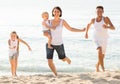 parents with two kids jogging on beach . Royalty Free Stock Photo