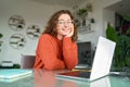 Young smiling pretty woman student sitting at table at home office with laptop. Royalty Free Stock Photo