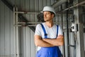 Young smiling professional in overalls and protective helmet standing in front of camera inside large machinebuilding plant Royalty Free Stock Photo