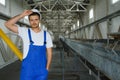 Young smiling professional in overalls and protective helmet standing in front of camera inside large machinebuilding plant Royalty Free Stock Photo