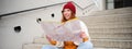 Young smiling redhead girl, tourist sits on stairs outdoors with city paper map, looking for direction, traveller Royalty Free Stock Photo