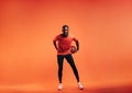 Young smiling sportsman dribbling basket ball in studio over orange background Royalty Free Stock Photo