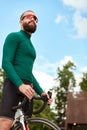 Young smiling sporty man in glasses with beard standing with bike in summer park, cardio workout on bike, city walks Royalty Free Stock Photo