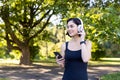 Young smiling sporty woman going for morning run and exercise. Standing in the park wearing headphones and holding a Royalty Free Stock Photo