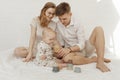 Young smiling stunning family with cherubic infant baby playing with modern pastel colorful silicone bowls