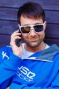 Young smiling stylish man in modern blue oufit making a phone call.