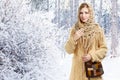 Young smiling stylish woman in openwork shawl and long beige sweater with checkered motley knitted bag stands in winter snowy for Royalty Free Stock Photo