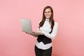 Young smiling successful beautiful business woman in glasses holding using laptop pc computer isolated on pink Royalty Free Stock Photo