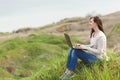 Young smiling successful smart business woman or student in light casual clothes sitting on grass using laptop in field Royalty Free Stock Photo