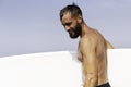 Young smiling surfer holding his surfboard on the beach - Handsome hipster man waiting waves for surfing - Sporty bearded man Royalty Free Stock Photo