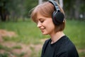 Young smiling teen girl in wireless headphones listening to music and meditating in the Park, photography for ad or blog Royalty Free Stock Photo