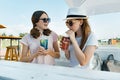 Young smiling teen girls drink cool refreshing summer drinks on a hot sunny day in summer outdoor cafe Royalty Free Stock Photo