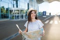 Young smiling traveler tourist woman in hat hold paper map, looking aside at international airport. Female passenger Royalty Free Stock Photo