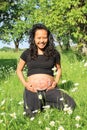 Smiling pregnant woman with drawing of baby on belly on meadow Royalty Free Stock Photo