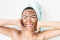 Young smiling woman applying coffee scrub mask on face - Happy girl having skin care spa day at home Royalty Free Stock Photo