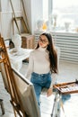 Young smiling woman artist, holding paintbrush and draws on canvas , working on a home studio Royalty Free Stock Photo