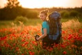 Young smiling woman with backpack and walking sticks stands on field of poppies Royalty Free Stock Photo