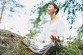 Young smiling woman with beads practice yoga outdoors in the forest. New normal social distance. Physical and mental health Royalty Free Stock Photo