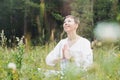 Young smiling woman with beads practice yoga outdoors in forest. New normal social distance. Physical and mental health Royalty Free Stock Photo