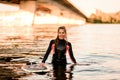 Young smiling woman in black wetsuit stands in the water. Royalty Free Stock Photo