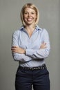 Young smiling woman in a blue shirt and trousers. Business success. Gray background. Vertical Royalty Free Stock Photo