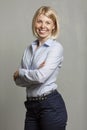 Young smiling woman in a blue shirt and trousers. Business success. Gray background. Vertical Royalty Free Stock Photo