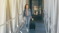 A young smiling woman is boarding with her trolley or suitcase Royalty Free Stock Photo