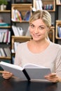 Young smiling woman is busy reading